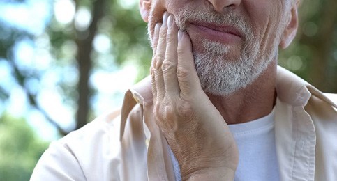 Man rubbing his jaw because shifting teeth are causing aches