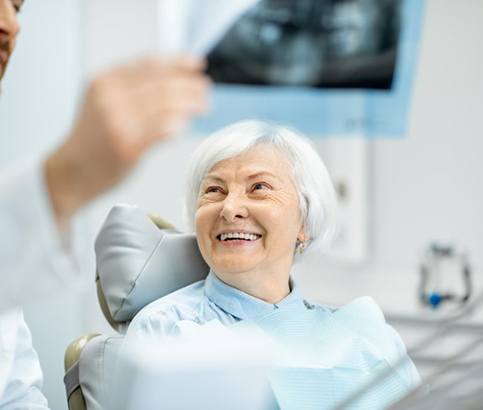 a patient smiling while her dentist shows her an X-ray