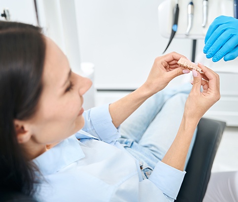Woman in dental chair holding sample replacement teeth