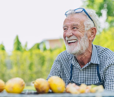 Senior man smiling outdoors with a couple of lemons